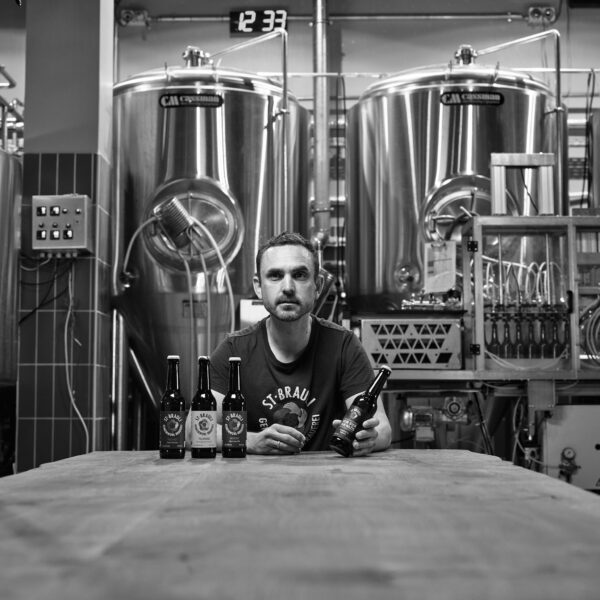 Markantes Schwarz-Weiß-Foto von Frieder Maier, 1. Vorsitzender des St. Brauli e. V., der in einer Brauerei sitzt.